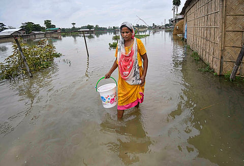 A woman walks through a flood-affected area, in Nagaon district of Assam, Tuesday, July 9, 2024.
